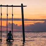 a girl on a swing surrounded by the sea