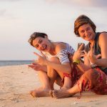 Girls goofing around on the beach while watching the sunset